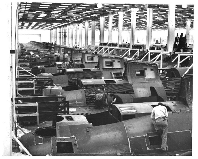 Spacious warehouse space full of rows of the metal shells of partially built boats.