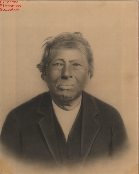 A sepia toned posed photograph of a middle aged man in a black suit against a white backdrop, looking into the camera.