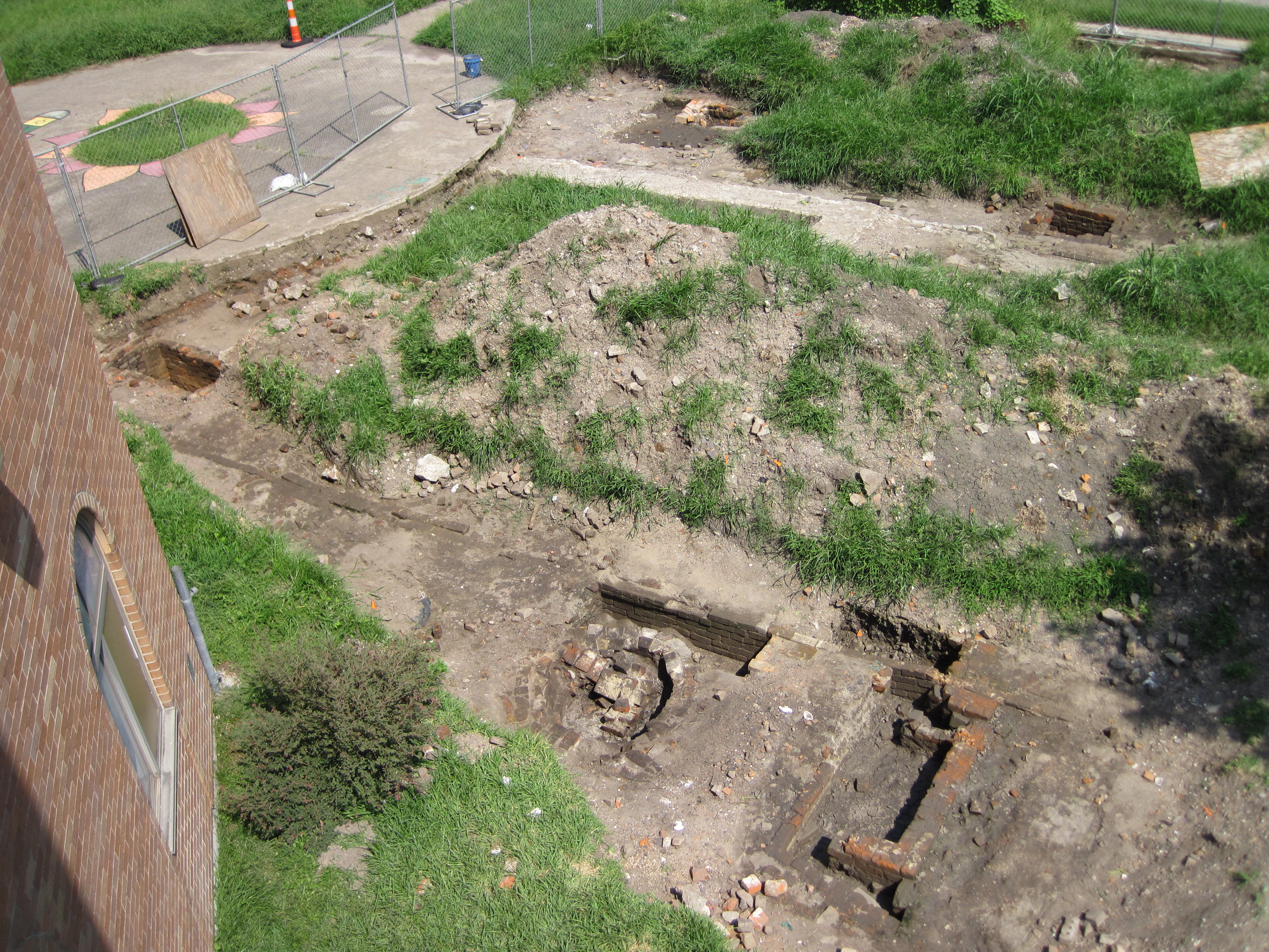 Image of school yard during archaeological investigation showing round and square brick features<br />
<br />