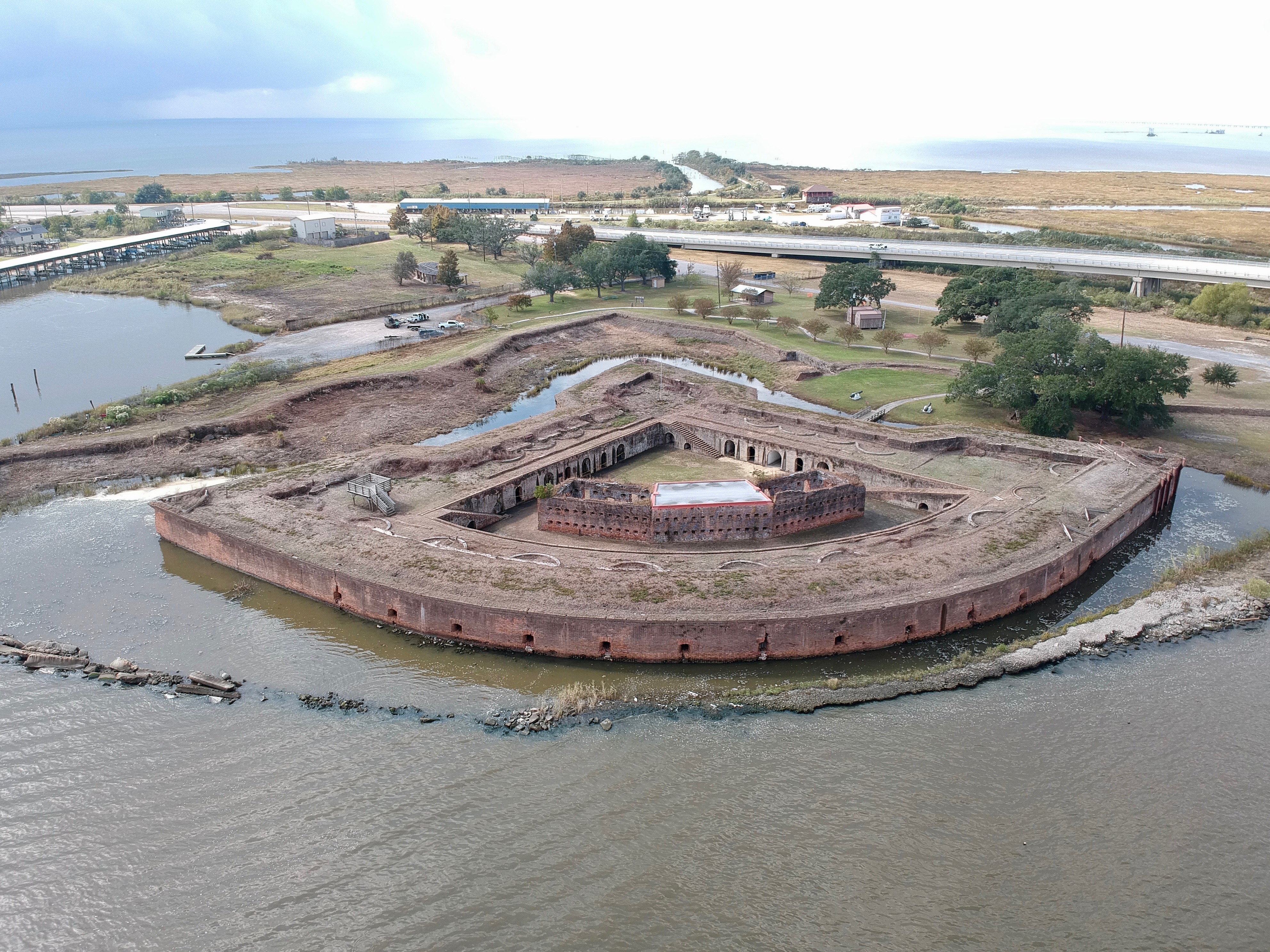 A brick fort the shape of a quarter circle surrounded by a moat on two sides and open water in its curved side.